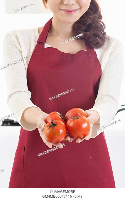 Young woman holding tomatoes with smile