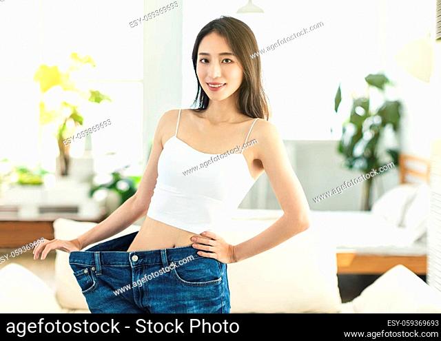 young woman succeeded in losing weight. She wore large size jeans long time ago, showed her figure very confidently