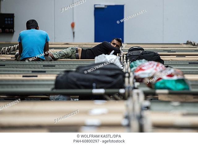 Refugees sit and lie on camp beds in one of the buildings of the gymnasium 'Hanns-Martin Schleyer Halle' in Stuttgart, Germany, 15 August 2015