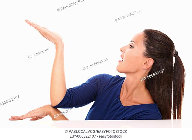 Pretty woman in blue shirt holding palm up while looking to her right in white background - copyspace