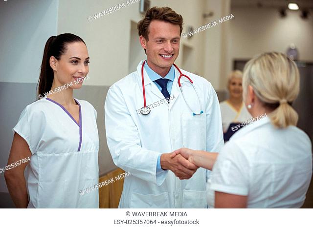 Doctor shaking hand with nurse in corridor