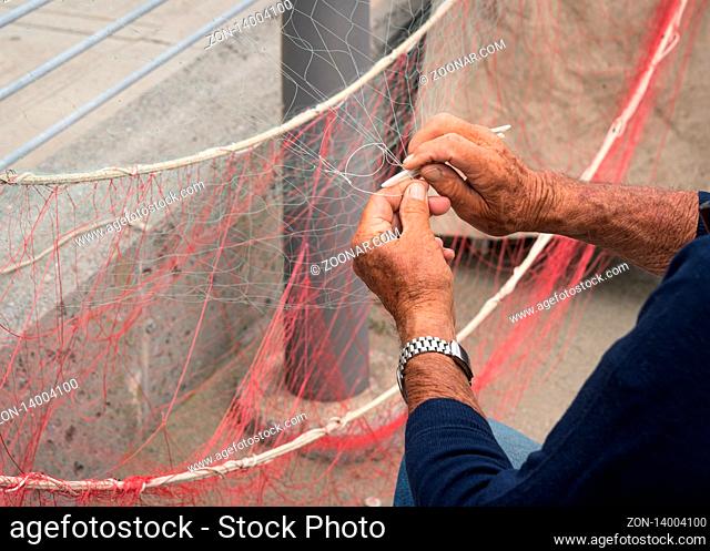 Old fisherman reparing fishing net
