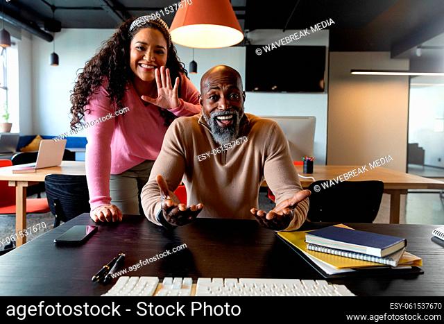 Portrait of smiling multiracial businessman and businesswoman discussing on video call in office