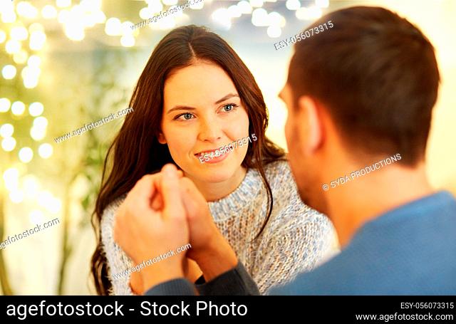 happy couple holding hands at restaurant or cafe