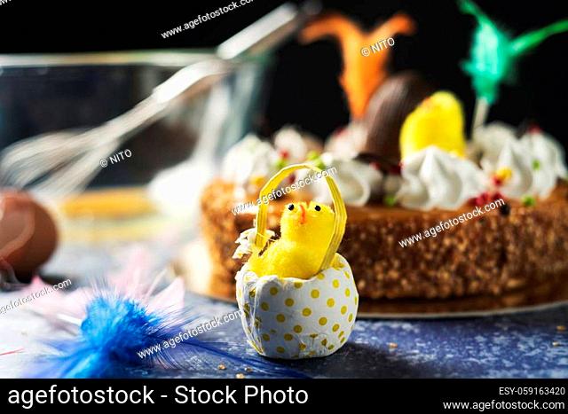 closeup of a plush chick on a table and a typical mona de pascua, a cake eaten in Spain on Easter Monday, decorated with a chocolate egg