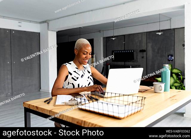 Smiling businesswoman working in modern office, using laptop