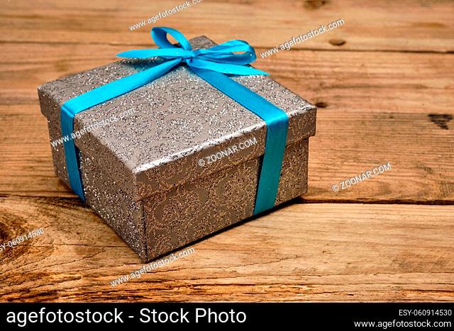 Gift birthday Christmas present concept - silver gift box with blue ribbon on old wooden background