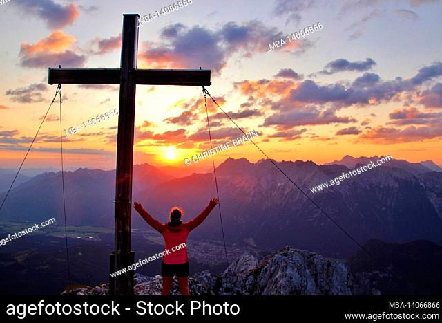 young woman, mountain cross in sunrise, hike, obere wettersteinspitze, 2.297m germany, bavaria, upper bavaria, werdenfelser land, mittenwald, isar valley