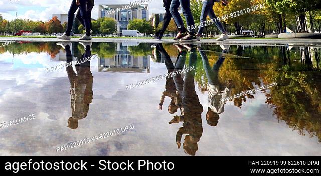 19 September 2022, Berlin: Tourists walk past puddles of rain in front of the Paul Löbe House at temperatures around 17 degrees Celsius
