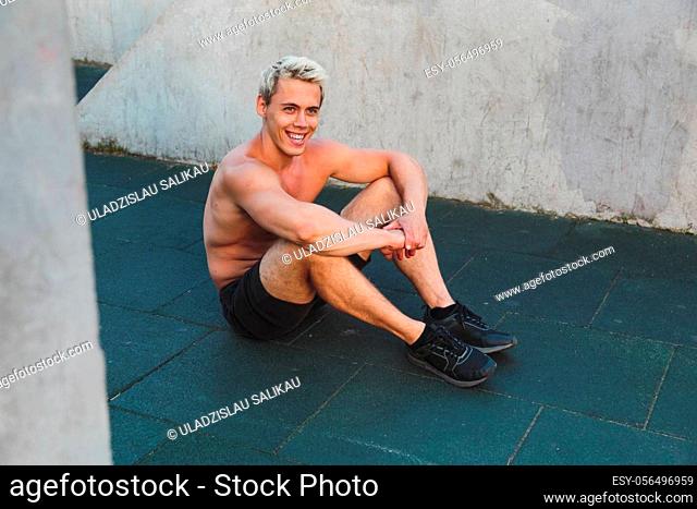 Young caucasian athlete man sitting on work out area outdoors
