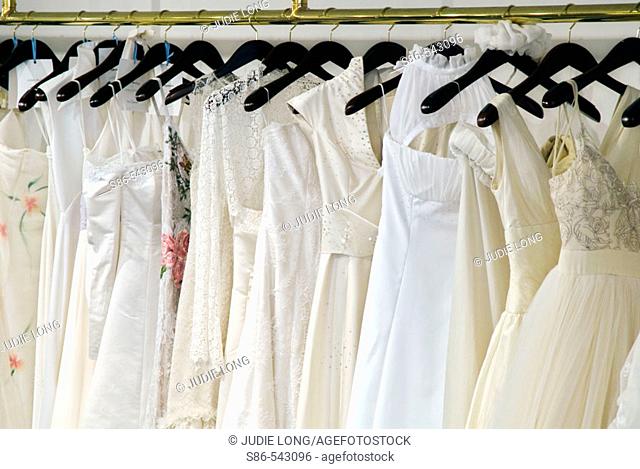 Bridal gowns hanging from a brass rack, in a retail store display