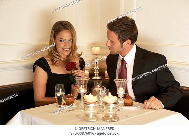 Couple in a restaurant, woman holding rose in her hand