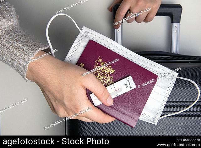 COVID-19, travel and lockdown concept, Young womans hand with passport, medical mask and negative rapid test coronavirus and suitcase, Travel, requirement