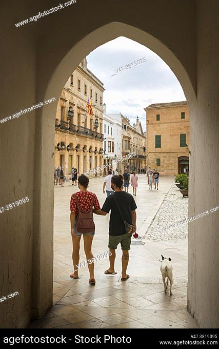 A young couple walking their dog through the old town of the Ciudadela, Menorca
