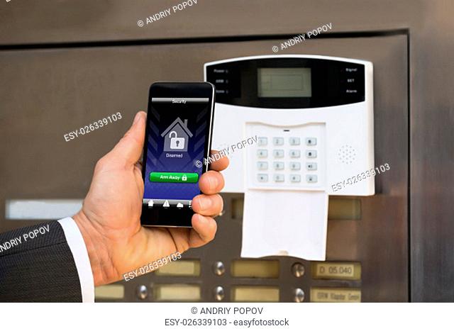 Close-up Of Businessperson Hand Holding Smartphone For Arming The System