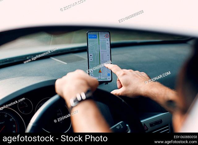 Navigator in car vehicle transportation commuter. Driver man using mobile phone navigator app while driving car