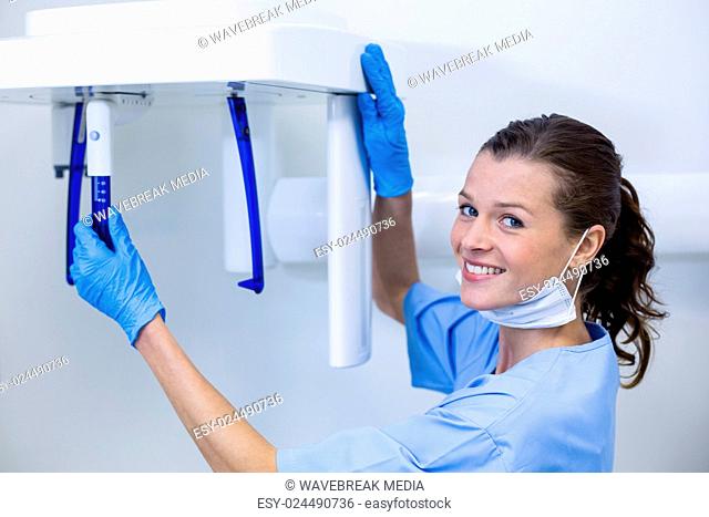 Dental assistant adjusting x-ray equipment