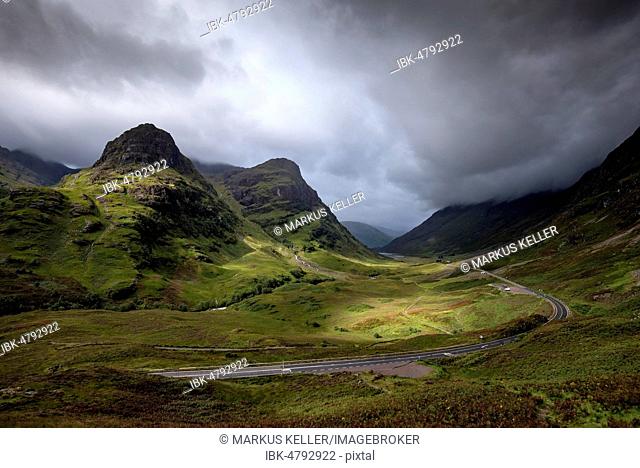 Dark clouds over the valley Glen Coe, road through mountainous countryside, Highlands, Scotland, Great Britain