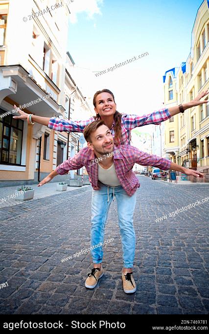 Close-up portrait of young caucasian man giving piggyback to woman. Young people resting in European country