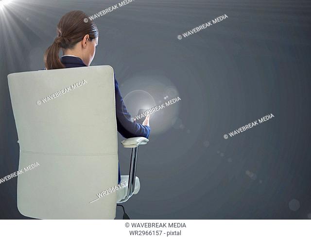 Back of seated business woman with phone against grey background with flares