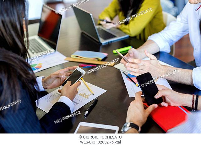 Business people using cell phones during a meeting in office