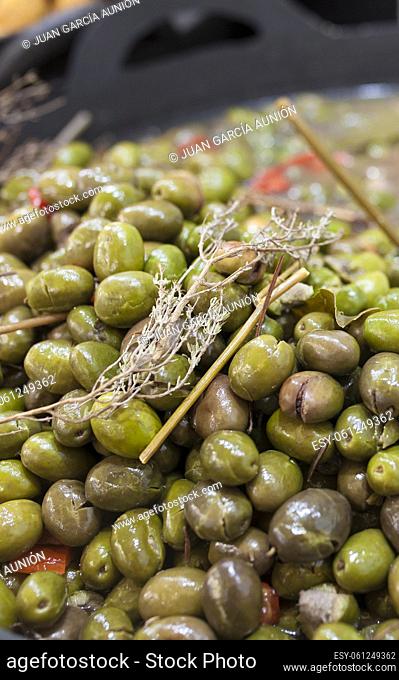 Green crushed marinated olives. Delicious pickled snack displayed plastic basket