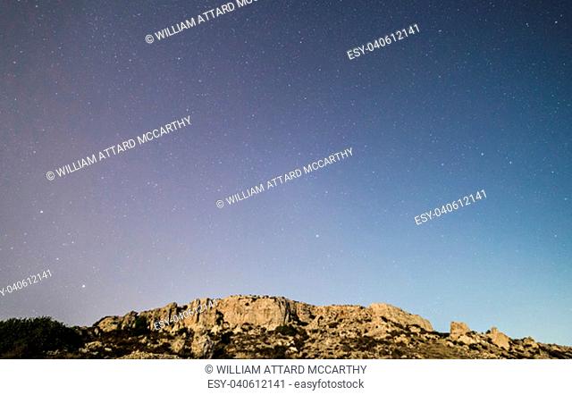 The cliff face at Mgiebah Bay in Malta, under a starry sky