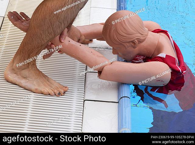 14 June 2023, Berlin: A young man demonstrates the procedure for rescuing a casualty on a mannequin while pre-swimming potential lifeguards at the Humboldthain...