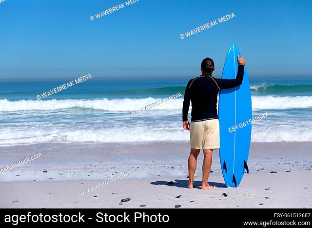 Senior Caucasian man holding a surfboard at the beach