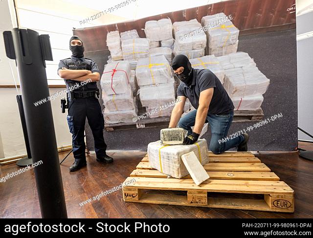 11 July 2022, Bavaria, Munich: A customs officer kneels in front of part of what has become the largest single seizure of cocaine in Bavaria to date