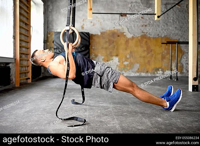 man doing exercising on gymnastic rings in gym