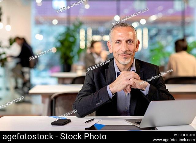 Businessman with hands clasped in office