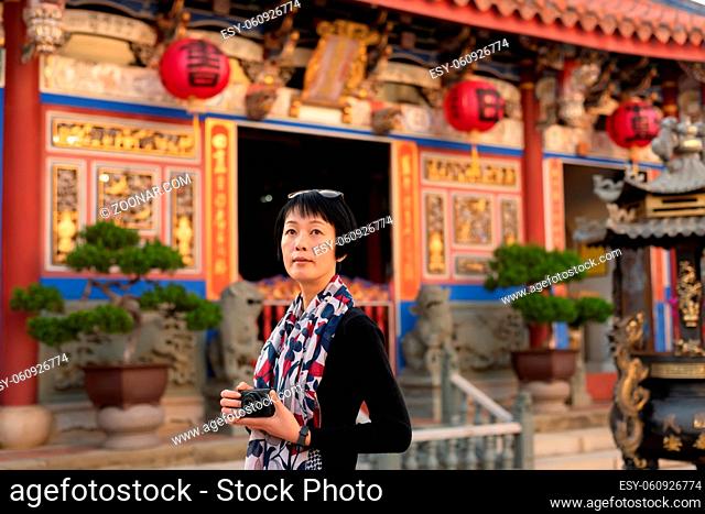 modern Asian woman hold a camera traveling at an old Chinese buildings