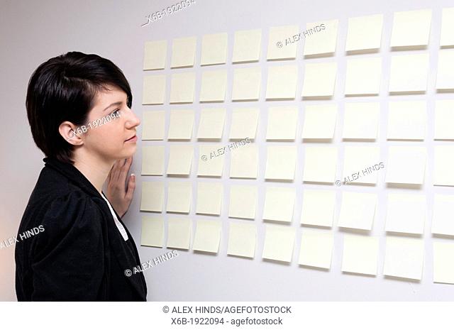 Young woman next to wall of sticky paper notes