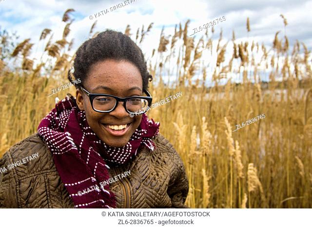 African American teenager girl dressed warm and laughing in front of a wheat field at the  Tryon Palace, New Bern, North Carolina, United States of America