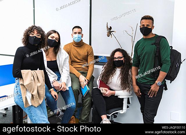 Male and female colleagues wearing protective face mask against white wall in office