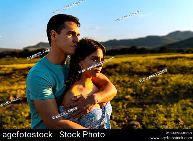 Young boyfriend embracing girlfriend from behind during sunny day