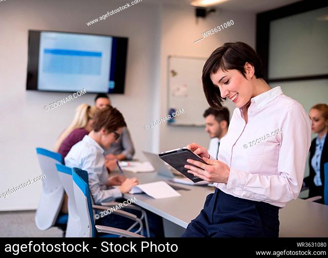 business woman on meeting usineg tablet computer, blured group of people in background at modern bright startup office interior
