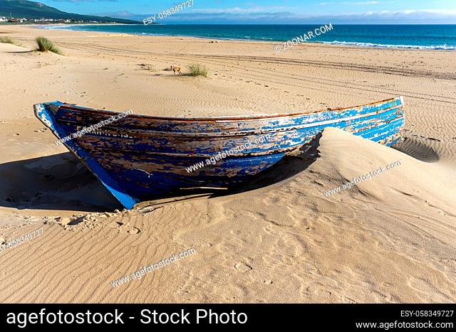 A colorful wreck of an old wooden rowboat buried in the sand