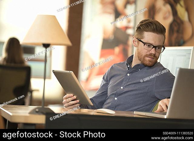 Caucasian businessman using digital tablet and laptop in office
