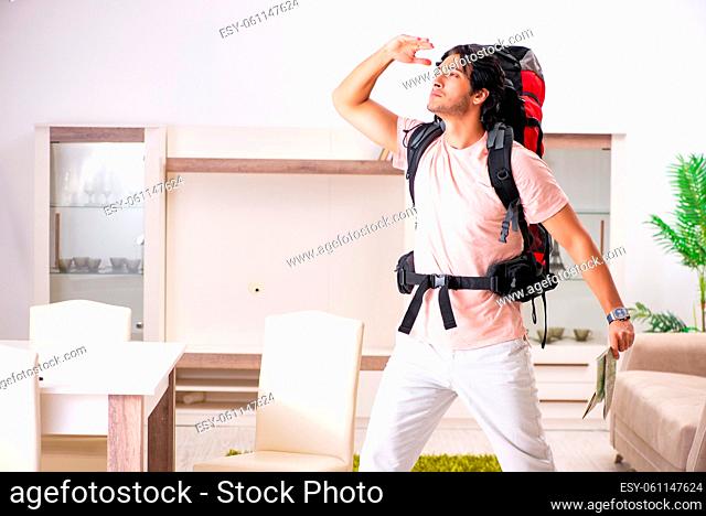 Young male tourist preparing for trip at home
