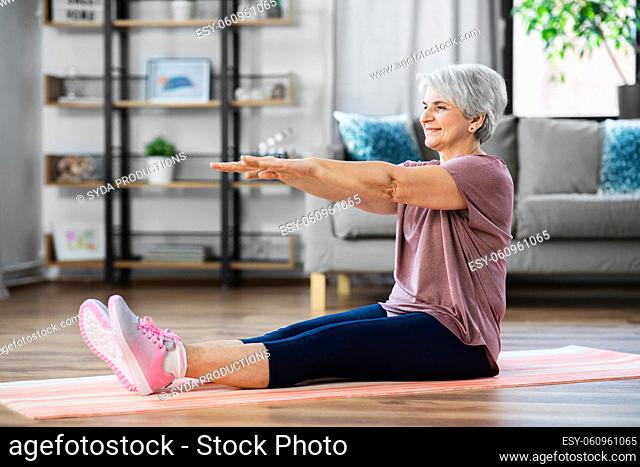 smiling senior woman exercising on mat at home