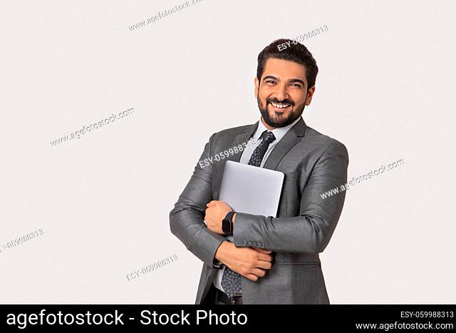 Portrait of a man in formal business suit standing holding a laptop