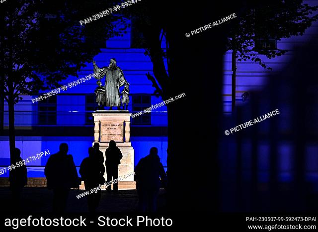 06 May 2023, Saxony-Anhalt, Halle (Saale): Visitors look at the illuminated monument to August Hermann Franke in the Frankesche Stiftungen