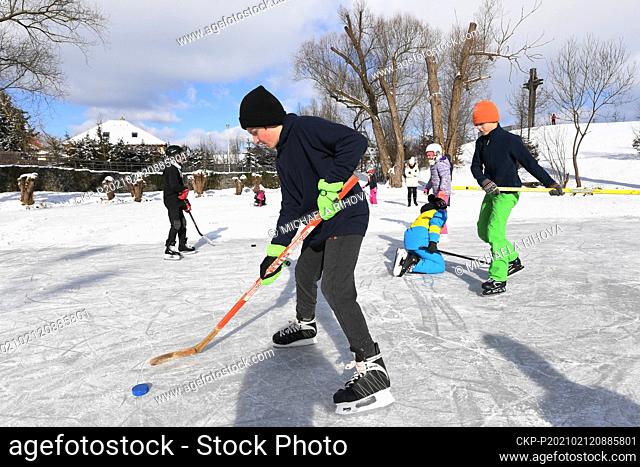 Children enjoy the sunny wintry weather and winter sports on the frozen pond in Dolni Brezany in Prague, Czech Republic, February 12, 2021