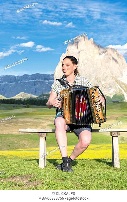 Alpe di Siusi / Seiser Alm, Dolomites, South Tyrol, Italy. Young woman playing with the accordion at the Alpe di Siusi