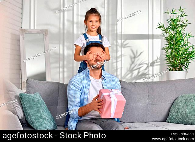 cute daughter congratulates her father and gives him gift box. happy dad and little child girl