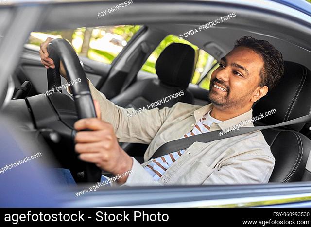 smiling indian man or driver driving car