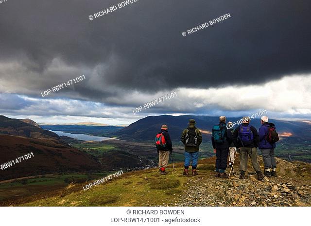England, Cumbria, near Keswick. A group of senior walkers standing on top of Barrow in the Lake District looking towards Bassenthwaite lake