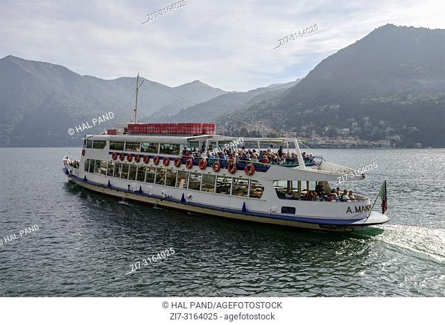 MOLTRASIO, ITALY - OCTOBER 03: fall sun lightens passenger vessel leaving landing at historical touristic village on Lario lake